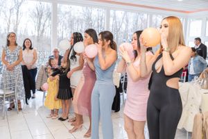 Group of guests participating in a baby shower game with balloons.