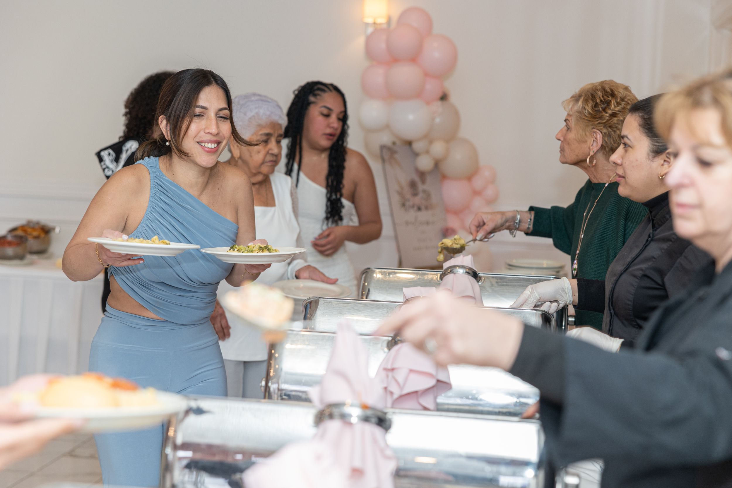 Guests serving food from buffet line at celebratory event.