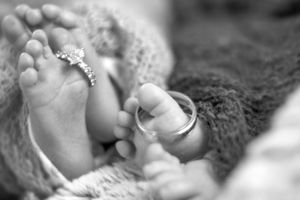 Close-up black and white photo of tiny newborn baby feet wrapped in soft fabric.