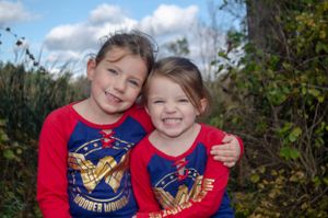 Two children wearing matching red and blue superhero shirts outdoors.