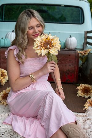 A collage of photos showing someone in a pink dress posing with golden sunflowers on a porch.