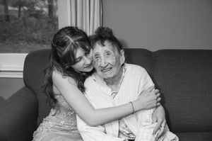 A tender embrace between two generations sharing a heartfelt moment on a couch in black and white photography.