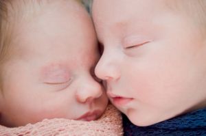 Close-up of two sleeping newborn babies in pink and blue.