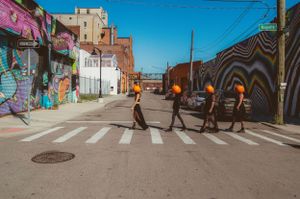 People crossing a street with colorful urban art murals and graffiti on surrounding buildings in a city setting.
