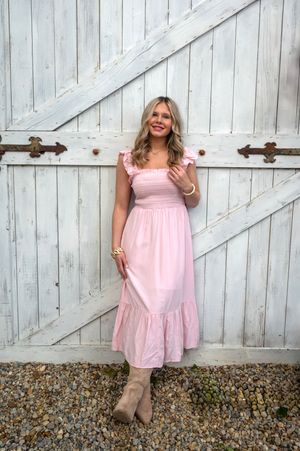 A pink summer dress is showcased in a collage of four photos against a white barn door backdrop.