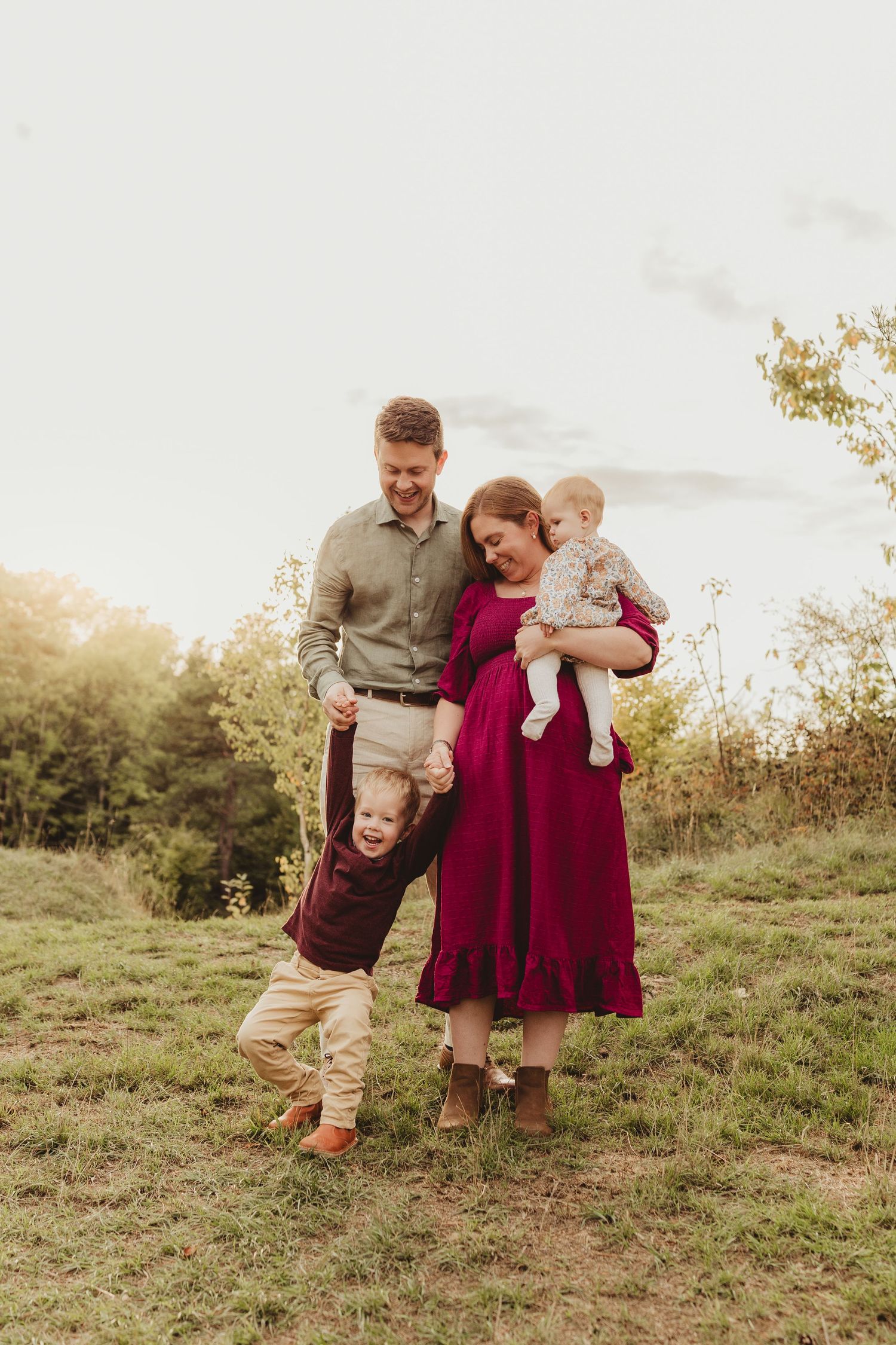 A joyful family runs and plays together in a sunlit meadow during golden hour.