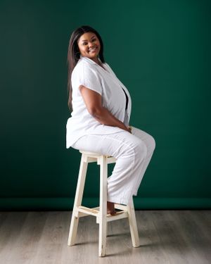 a lady in white seating on a white stool