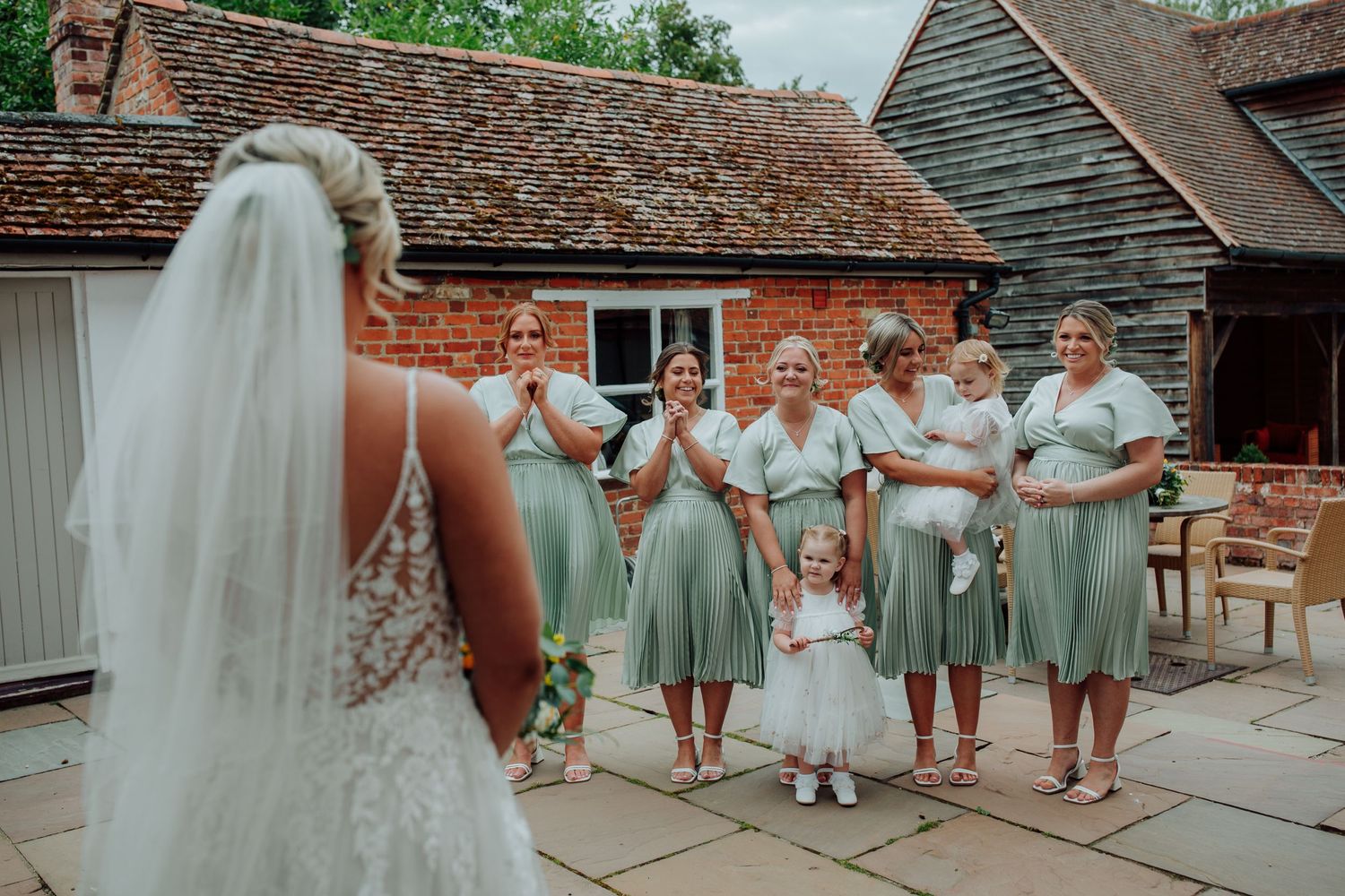 Wedding party in sage green dresses react joyfully during outdoor photo session. Houchins essex