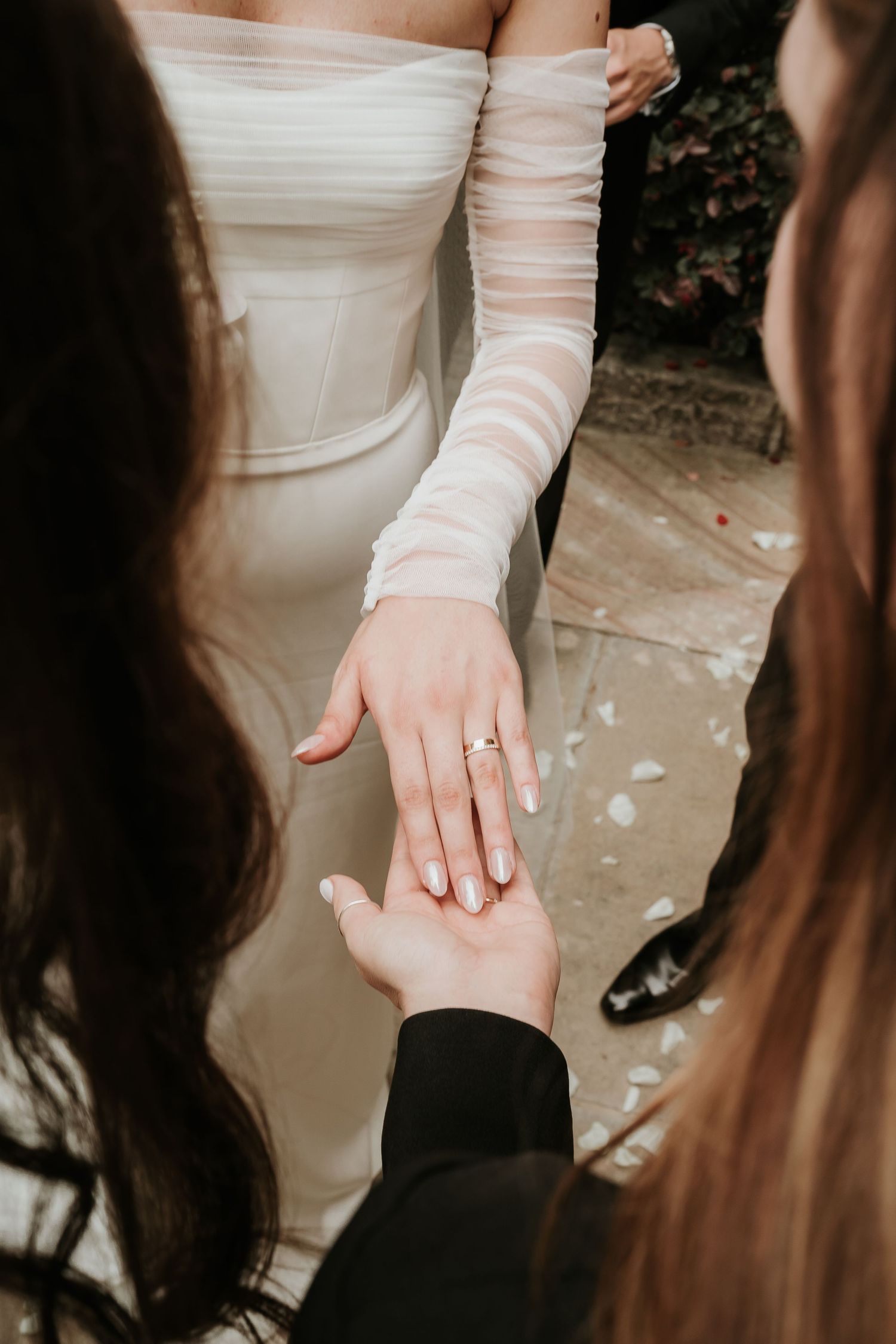 Close-up of a bride showing off her wedding ring while wearing elegant long white gloves.