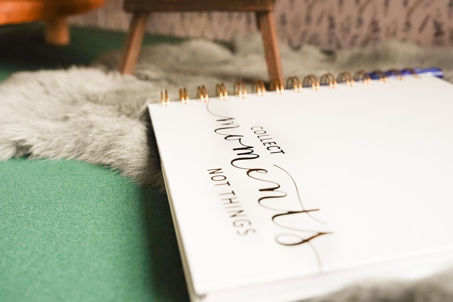 Spiral notebook with cursive text lying on green surface with fuzzy rug.
