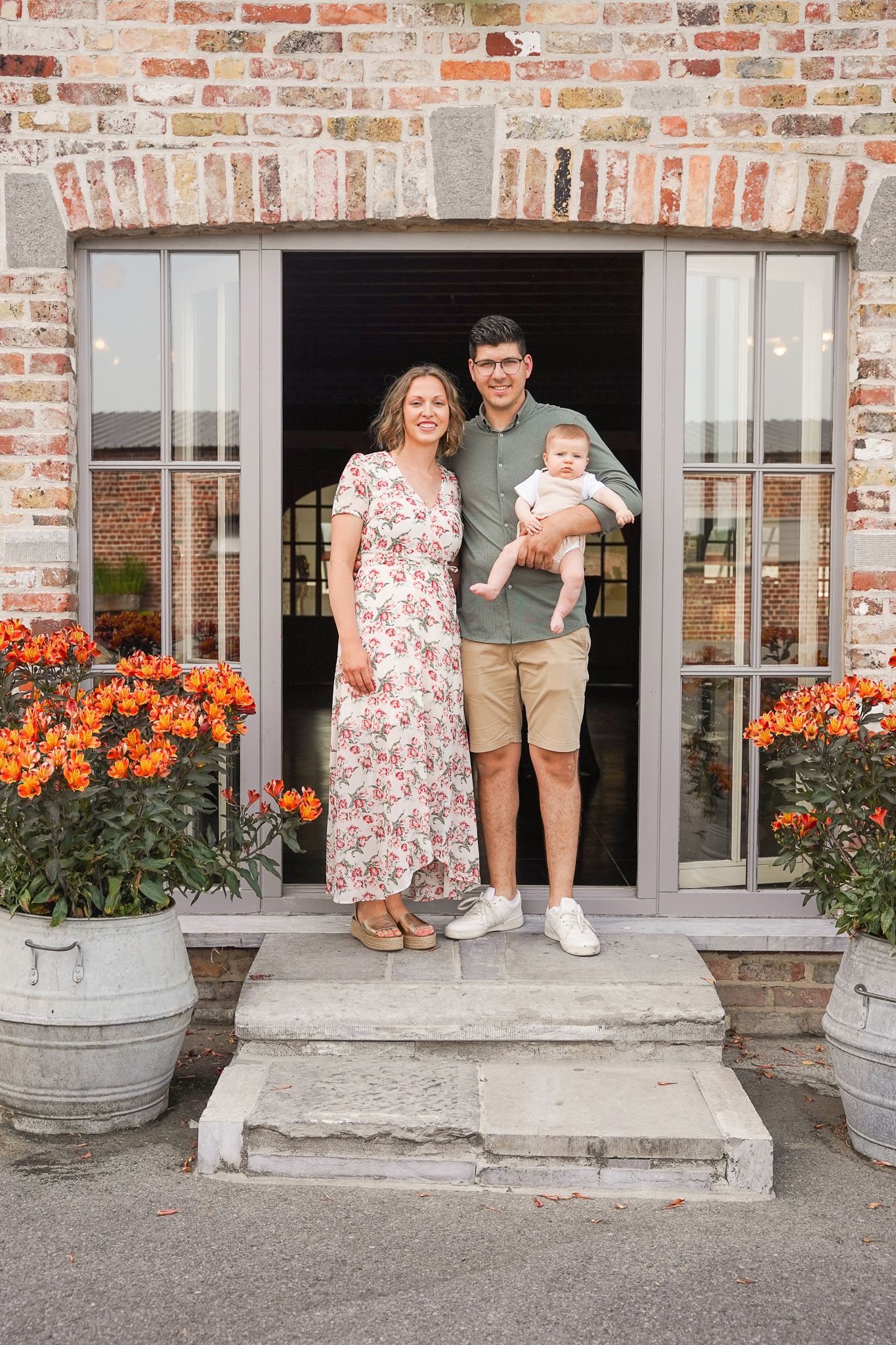 Family standing in doorway with orange flowers decorating the entrance.