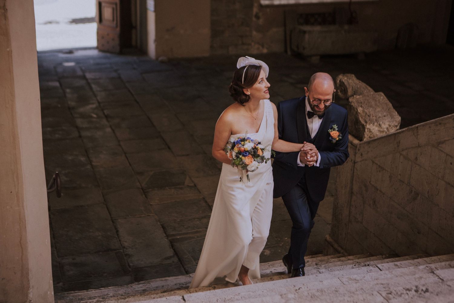 Couple walking together on stone steps during wedding ceremony.