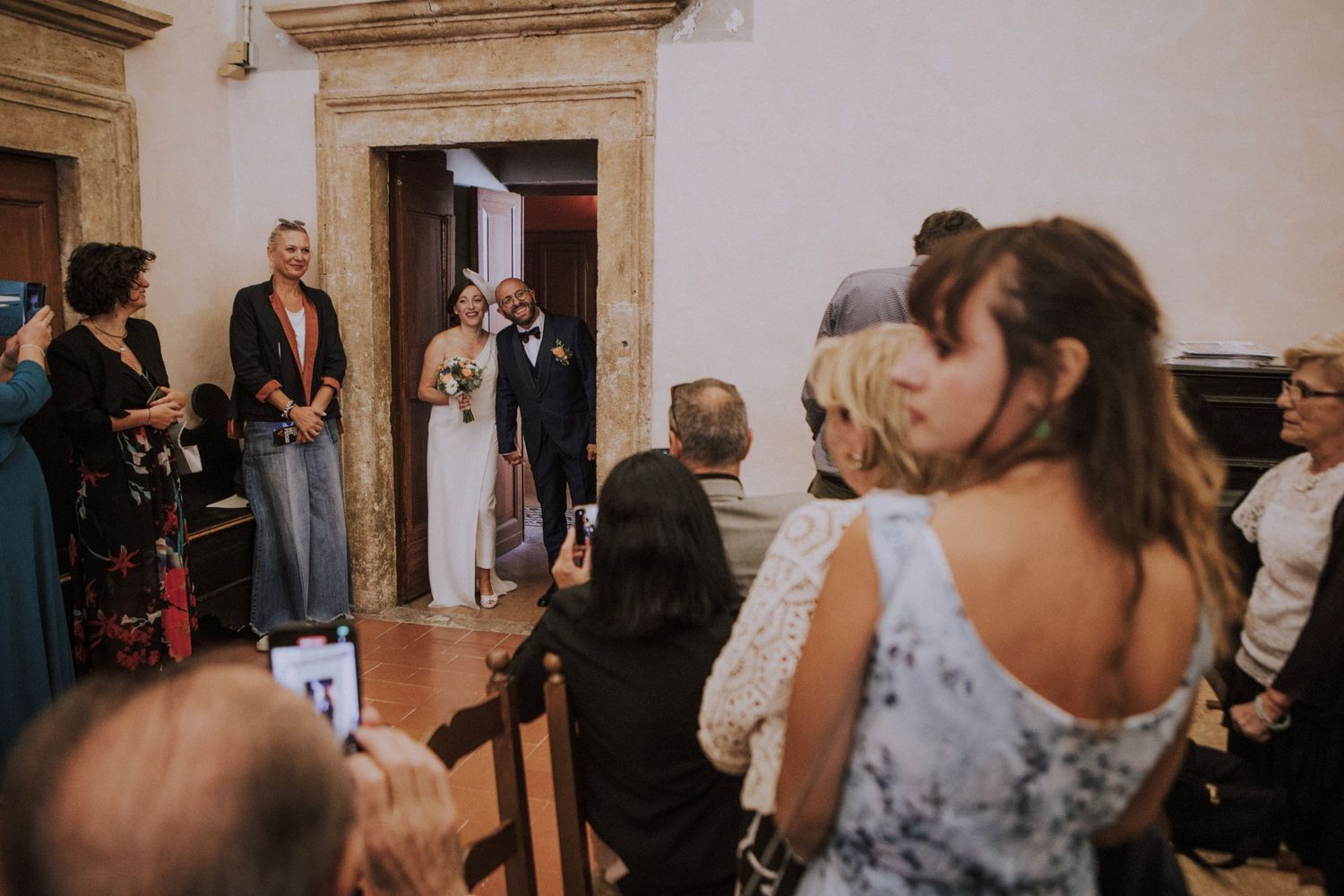 Wedding ceremony guests gathered in historic chapel with painted walls.
