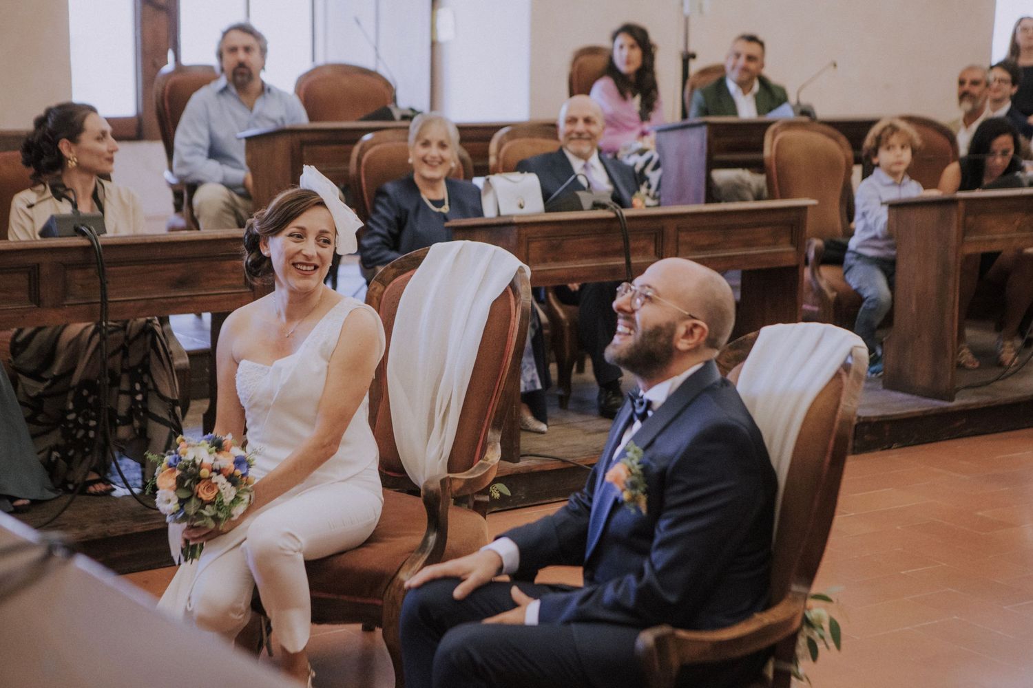 A couple shares a joyful moment during their wedding ceremony in an ornate church with wooden pews.