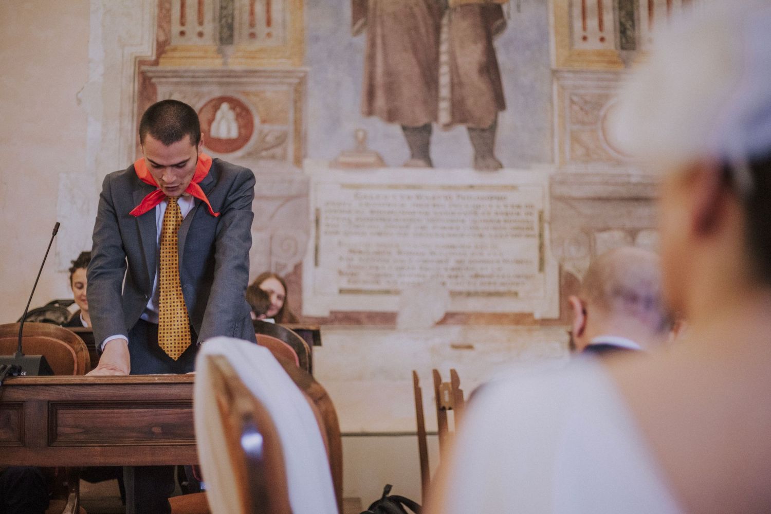 Two people share an intimate moment during a wedding ceremony in a historic church setting.