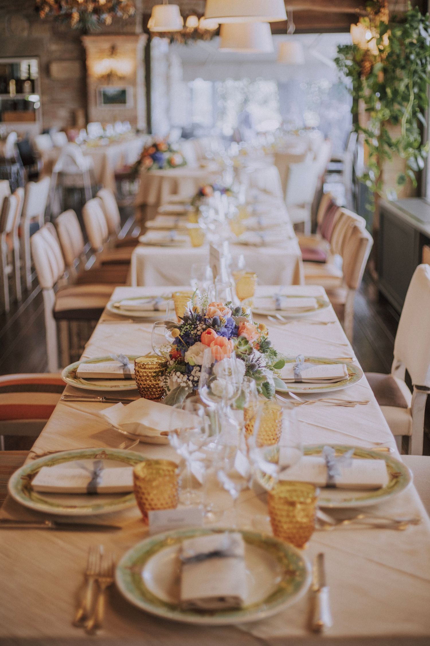 Elegant wedding reception table setting with floral centerpieces and amber glassware.