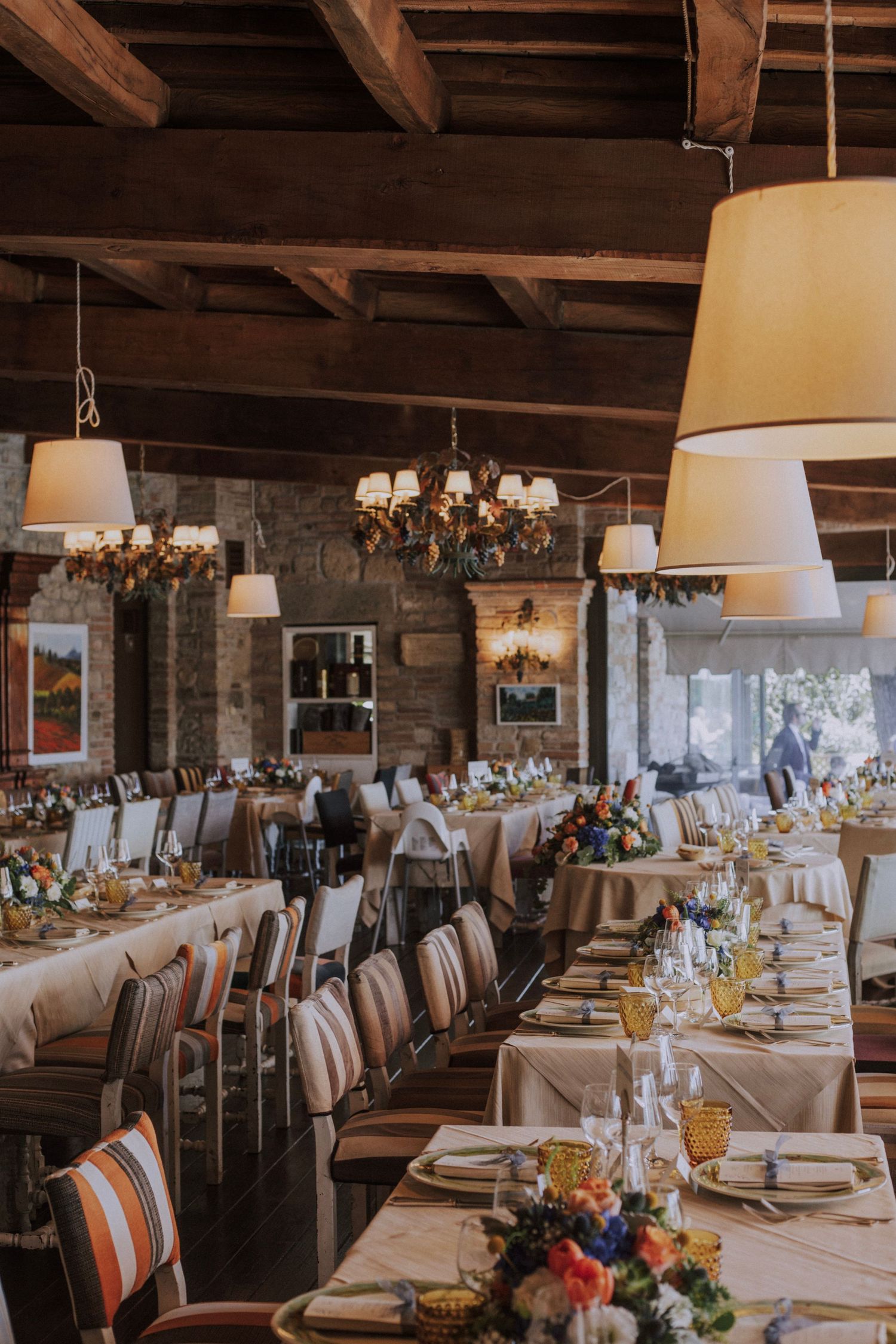 Rustic wedding venue interior with exposed wooden beams and elegant chandelier lighting.