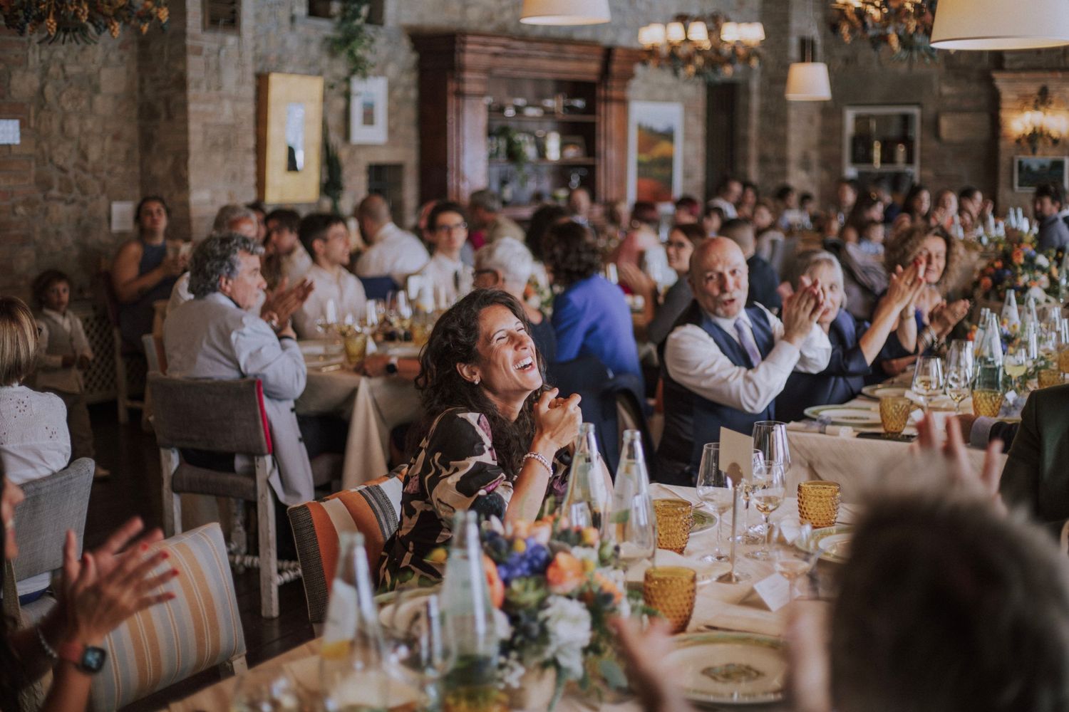 Wedding reception dinner with guests seated at decorated tables in rustic venue.