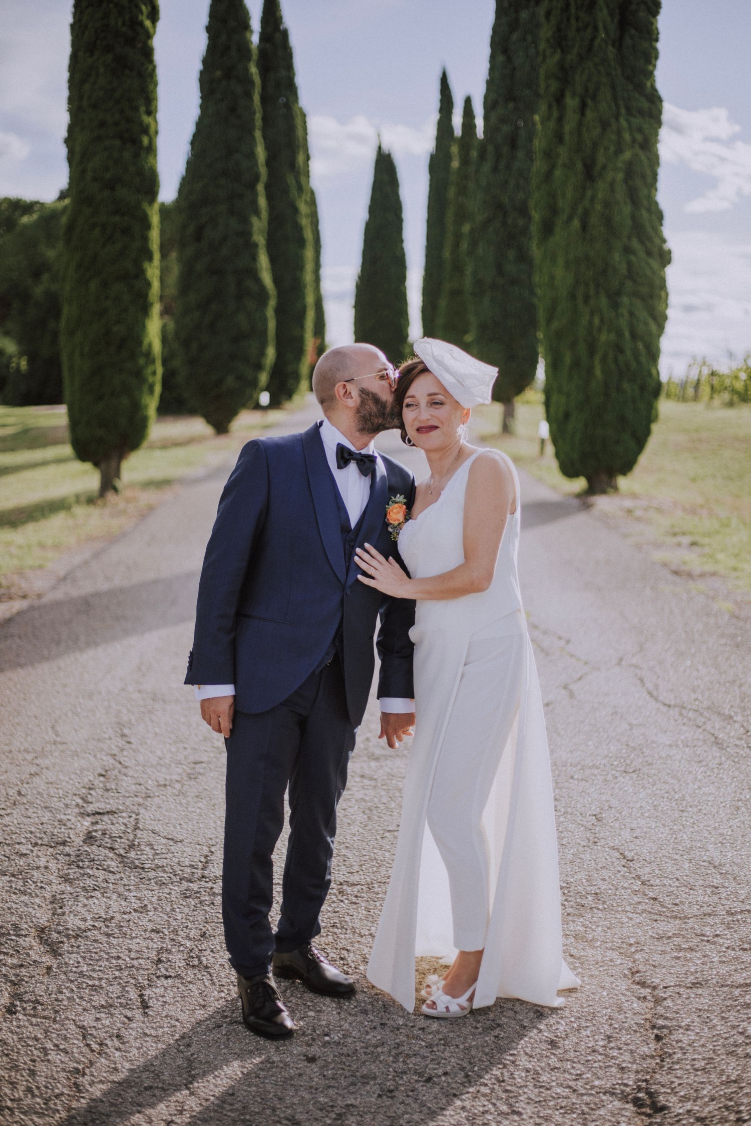 A joyful wedding moment captured between towering cypress trees on a country road.
