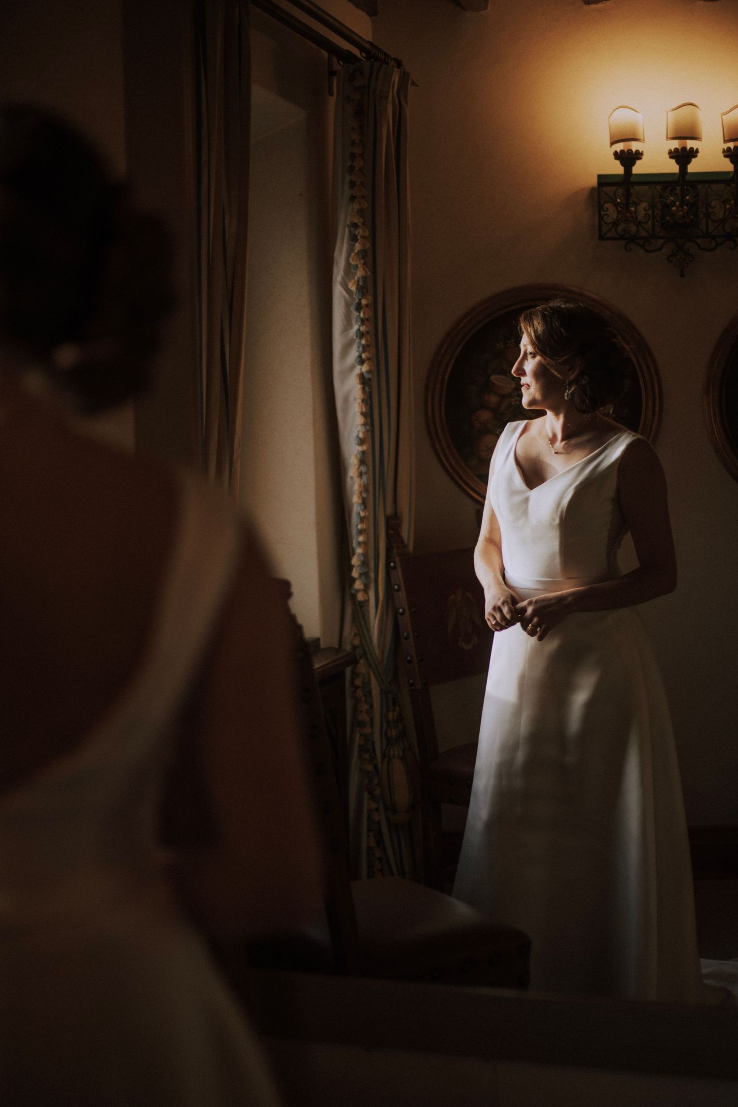 A soft, moody reflection of a bride in a white dress captured in a vintage mirror.