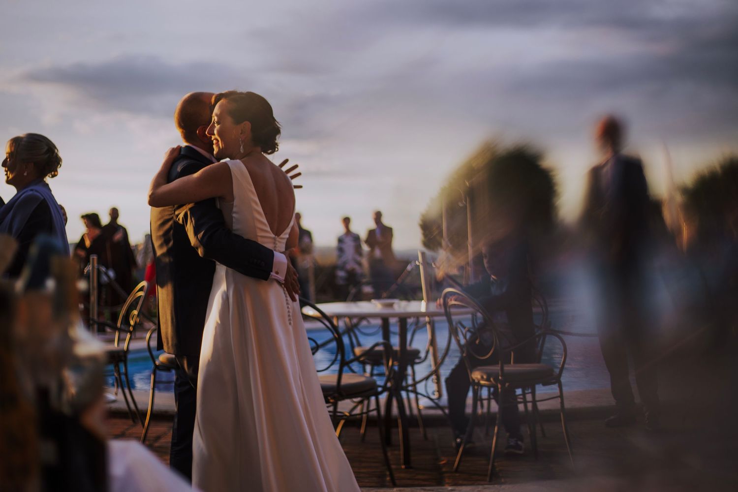 Couple embraces on outdoor dance floor during evening wedding reception.