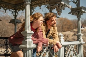Happy couple leaning on the railing of a decorative white gazebo in Central Park on a sunny day.