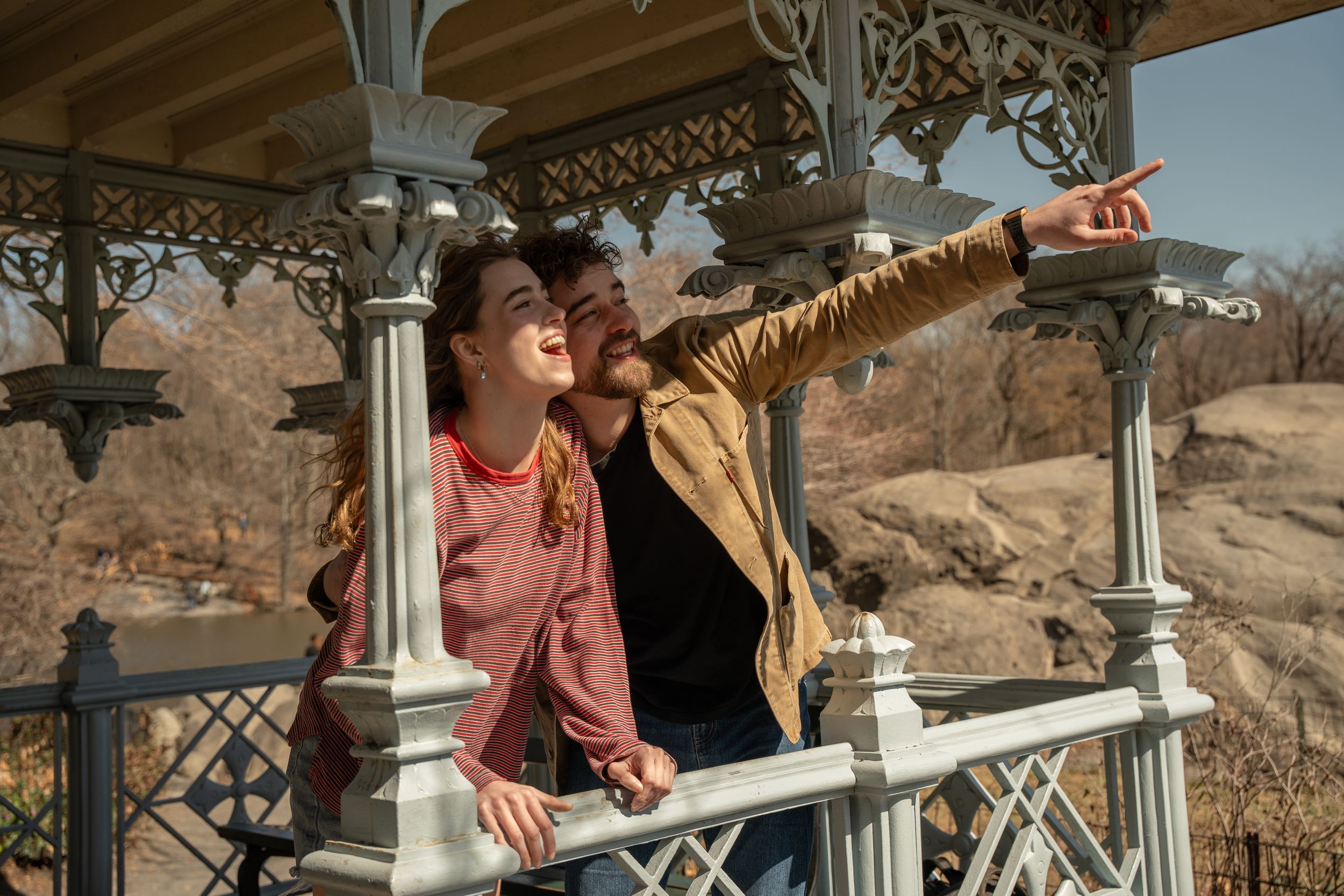 Couple sharing a romantic moment at an ornate gazebo in Central Park, man pointing at the view.