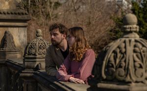 Couple standing close together at an ornate stone bridge railing in Central Park, sharing a quiet moment.