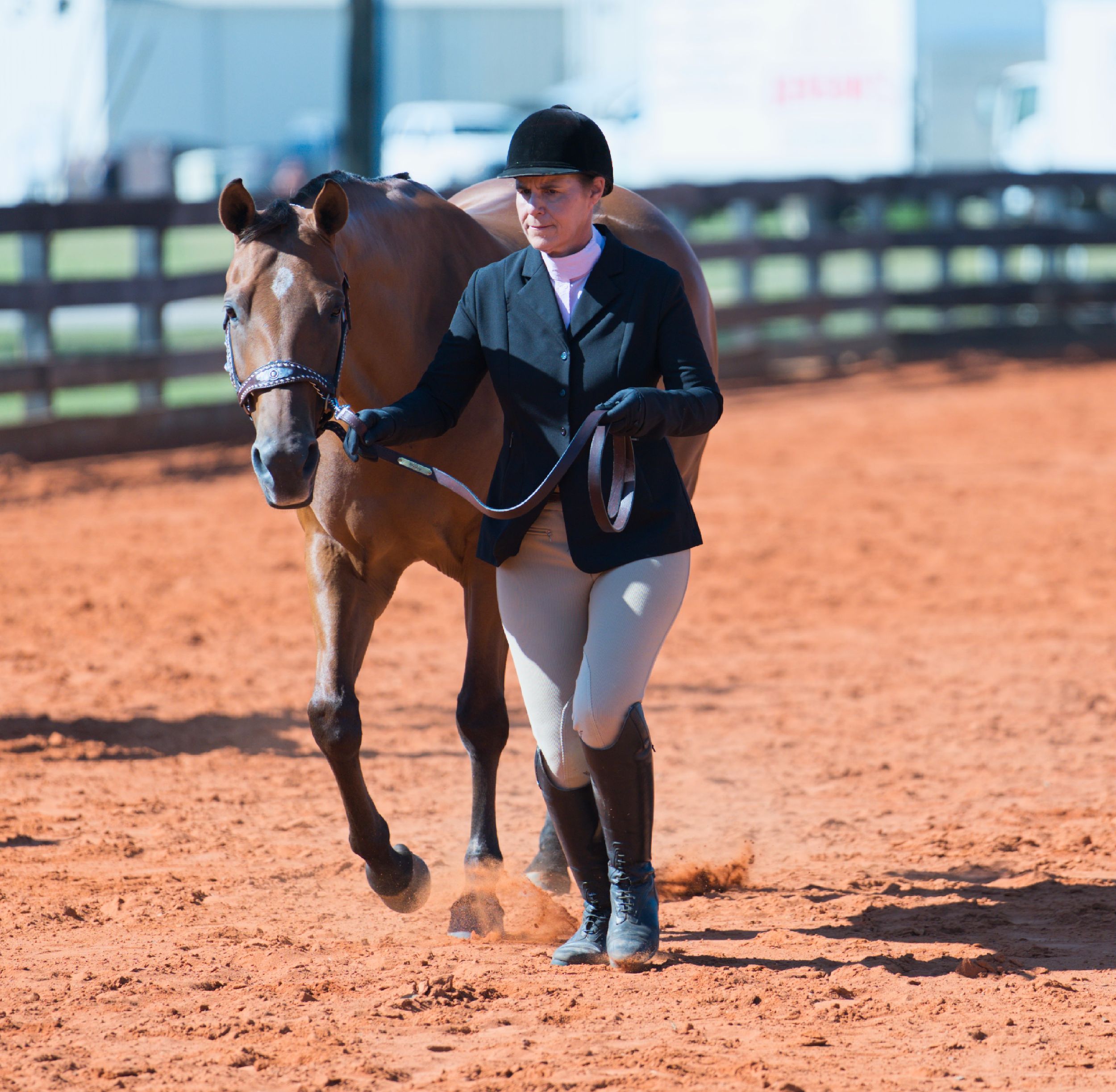 Close-up sequence of horse hooves and legs running on reddish dirt ground in an equestrian arena.
