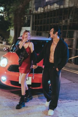 A series of photos showing people posing at night next to a red car with its headlights on一組照片顯示，人們在夜間與一輛亮著前燈的紅色汽車合影。