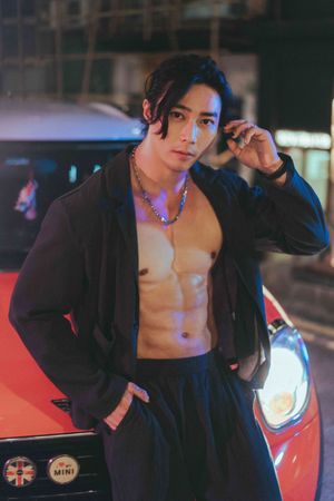 A person in a black blazer poses dramatically against a dark background with neon lighting effects.一名身穿黑色西裝外套的人在霓虹燈光效果的深色背景下擺出戲劇性的姿勢。
