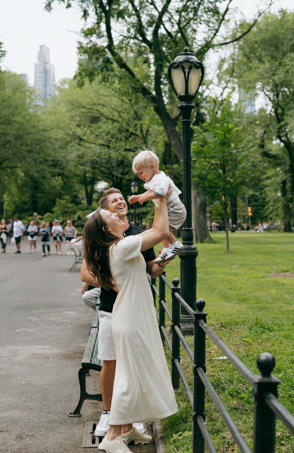 A joyful moment captured in Central Park with a decorative lamppost and city skyline visible in the background.
