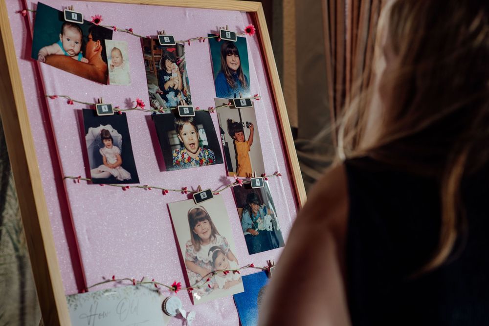 Person views a decorative memory board displaying childhood photos at a bridal shower celebration.