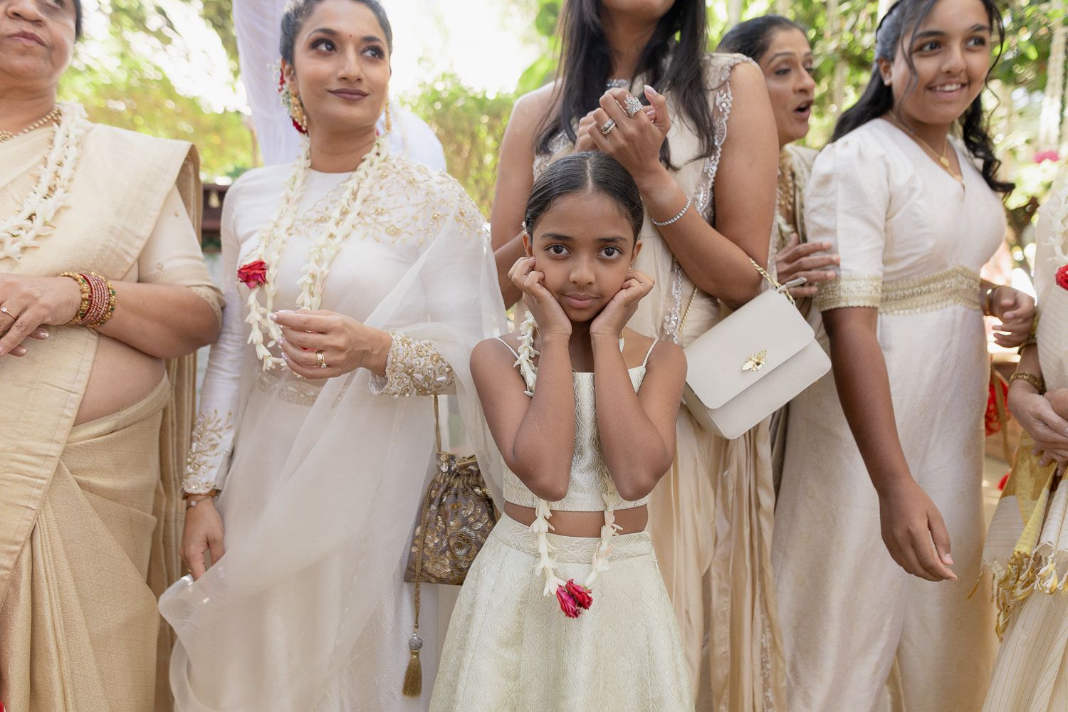 A group of people wearing traditional cream and white colored outfits gather together at a formal event.