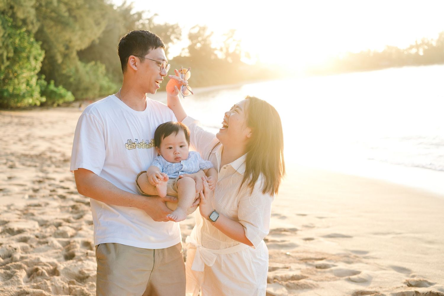 Family enjoying a sunset photoshoot together on a beautiful beach with golden light streaming through the scene.