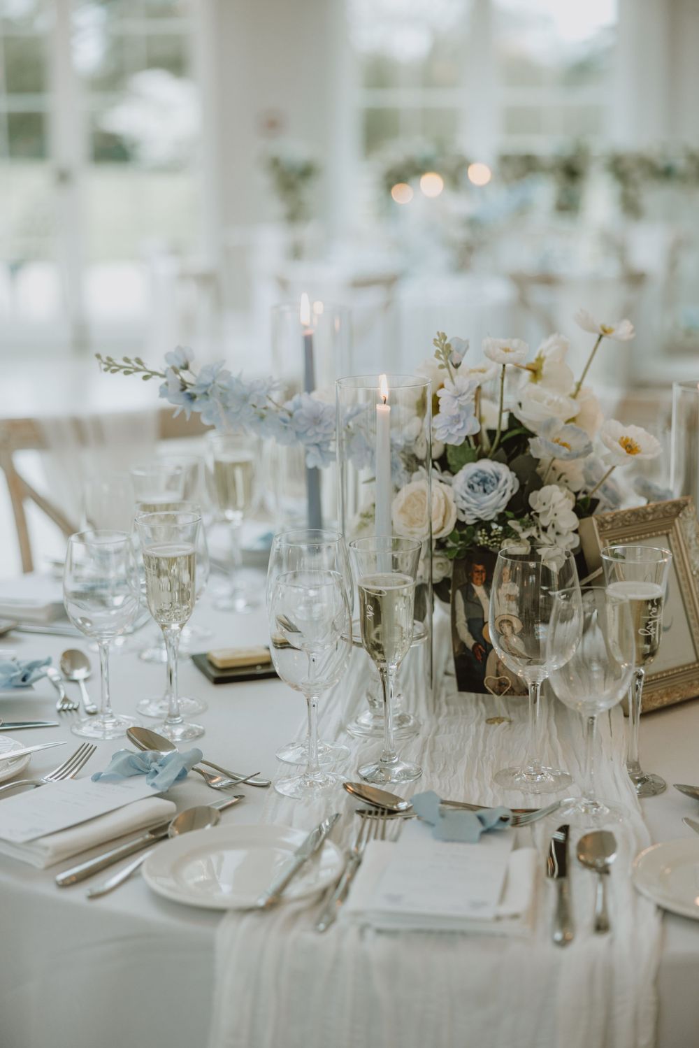 Elegant wedding reception table settings with white floral centerpieces, crystal glassware and formal place settings.