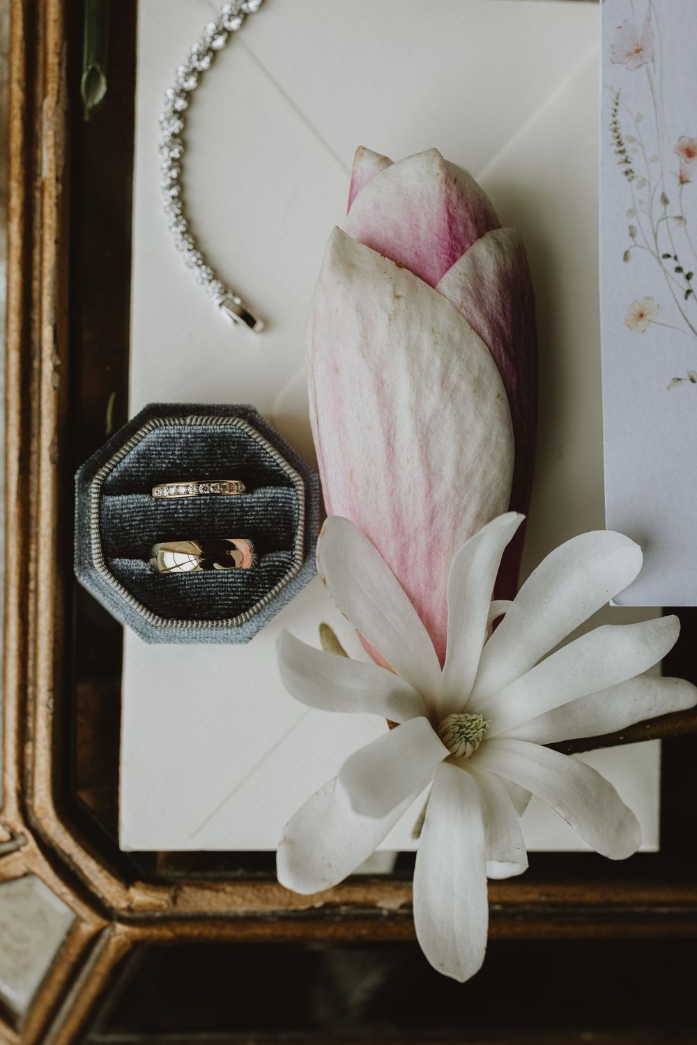 Wedding rings displayed in vintage octagonal ring boxes with delicate white magnolia flowers.