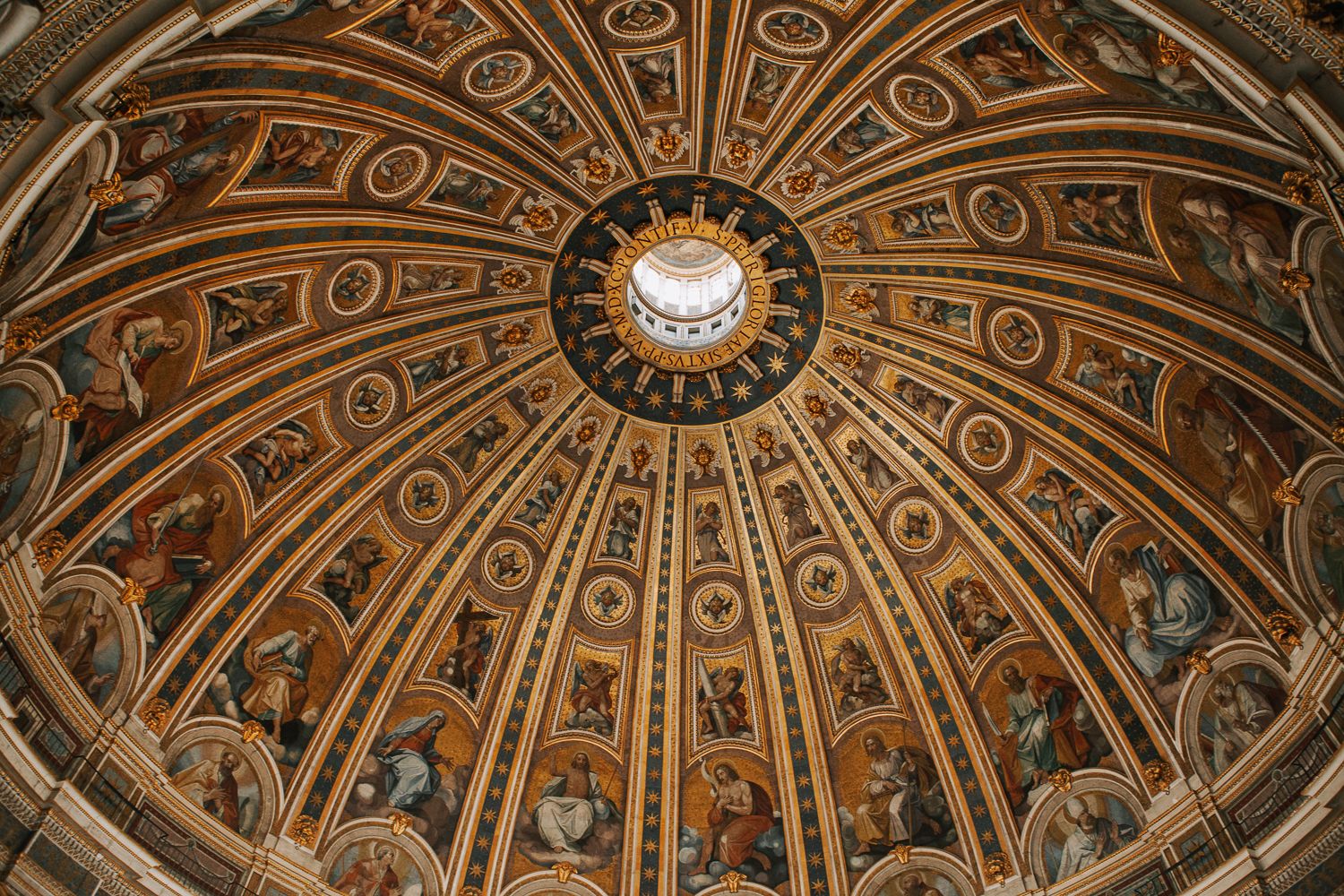 Ornate painted dome ceiling of St. Peters Basilica with golden mosaics and central oculus in Vatican City.