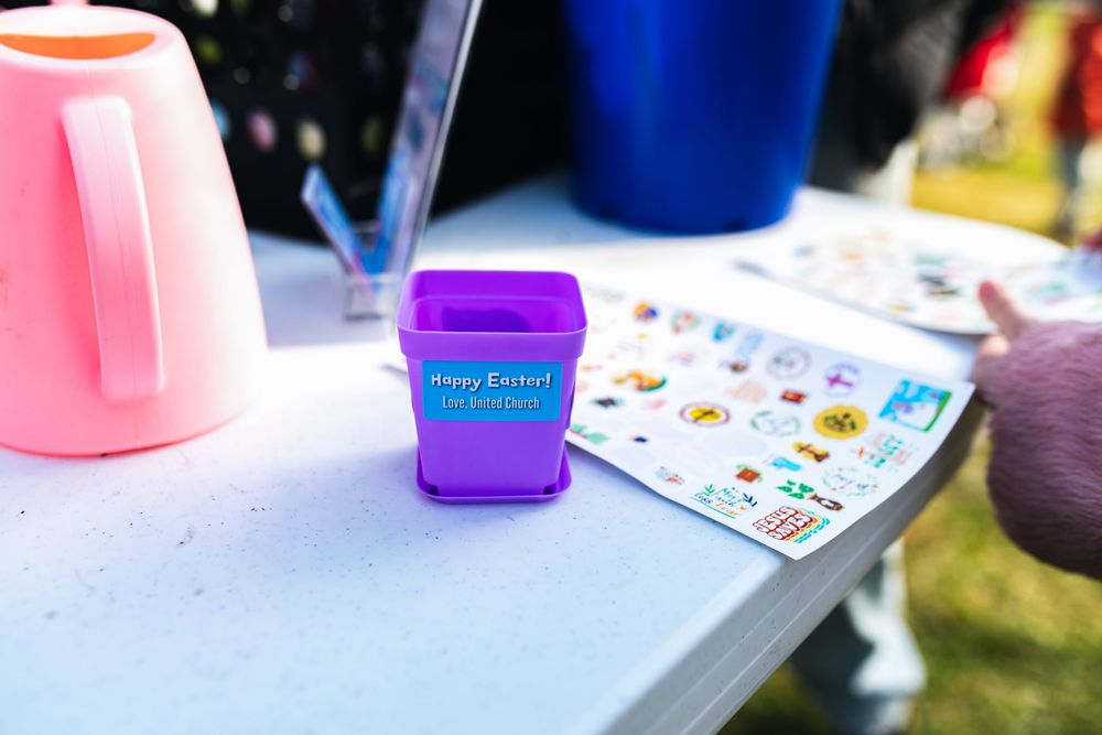 Purple Happy Easter bucket with sticker sheet on white table at outdoor Easter event.