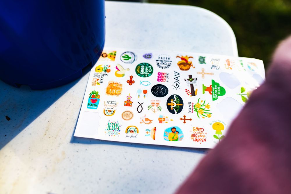 Colorful sticker sheet with various circular designs and icons displayed on a white surface outdoors.