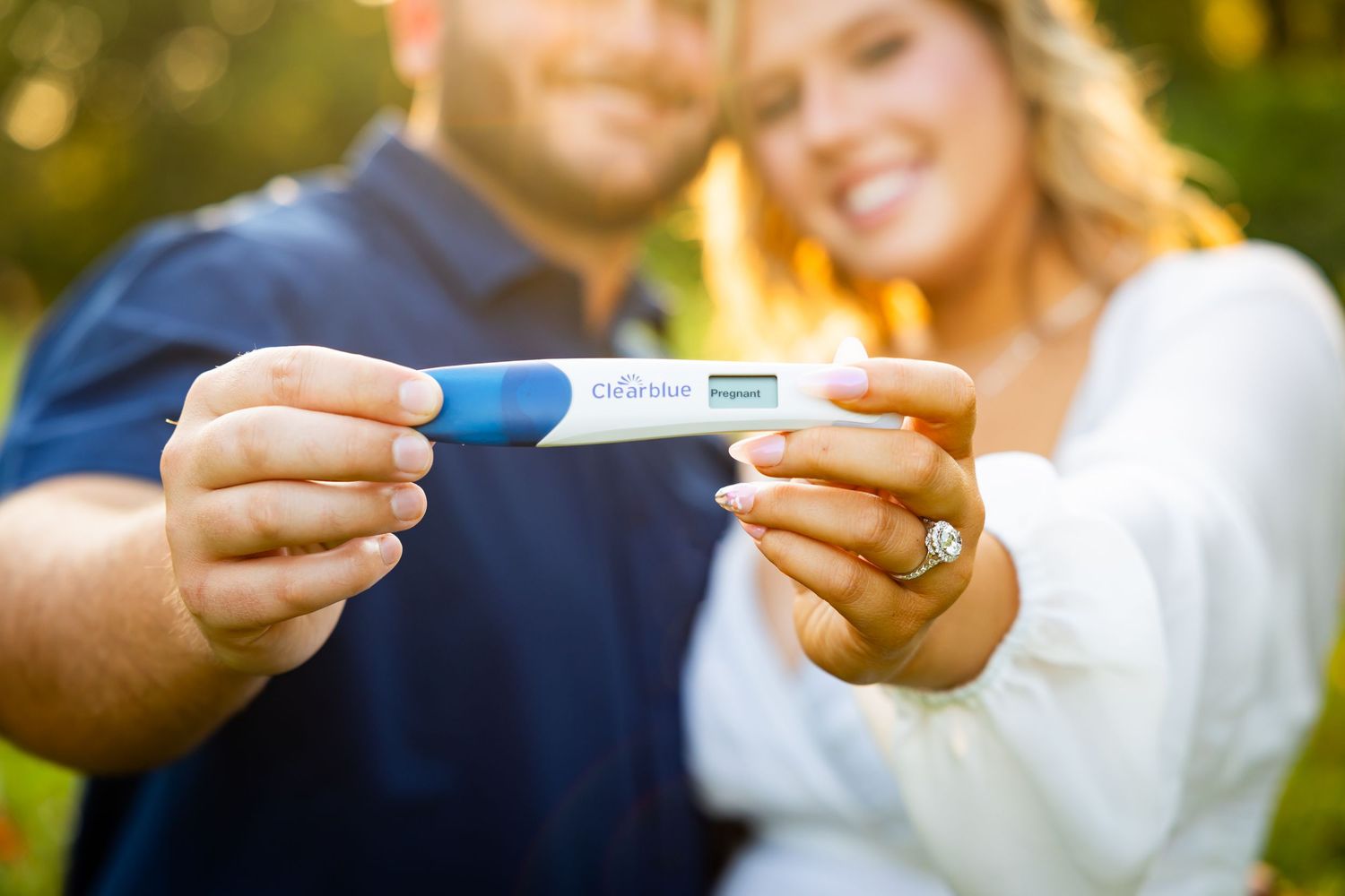 A couple exchanges wedding rings during an outdoor ceremony in a natural setting.
