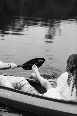 A person lying peacefully in a canoe on calm water, creating a serene black and white scene.