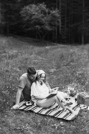 Two people share an intimate moment while laying on a blanket in a wildflower field.
