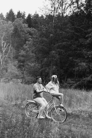 A vintage bicycle rests in a scenic meadow with forest trees in the background.
