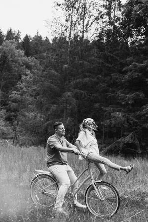 Black and white photo sequence showing playful moments with a vintage bicycle in a grassy field.