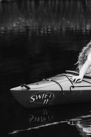 A series of black and white photographs showing close-up details of a kayak or canoe on dark water.