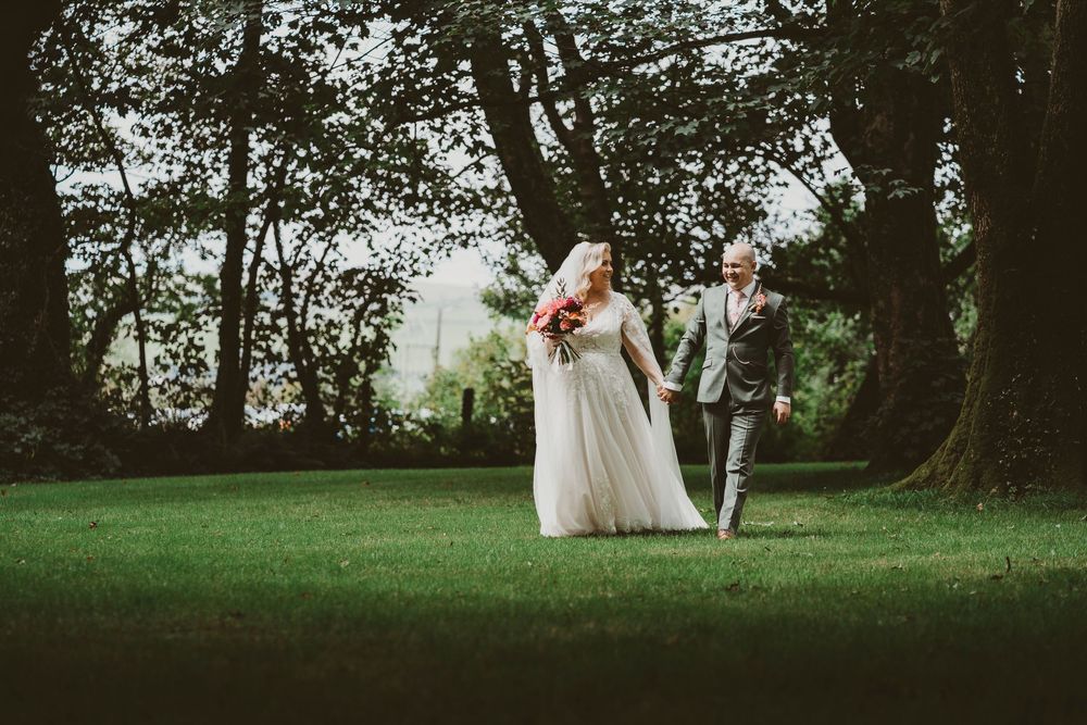 Bride and groom walking through woodland at Ceredigion West Wales wedding venue