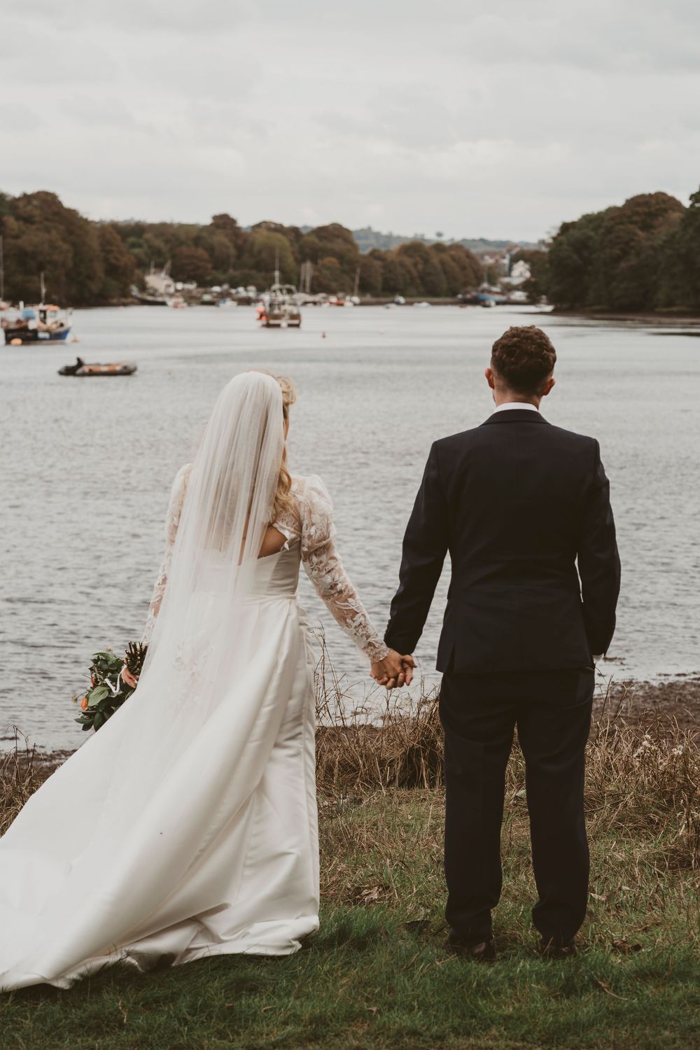 Bride and groom holding hands beside estuary during Ceredigion West Wales wedding photography
