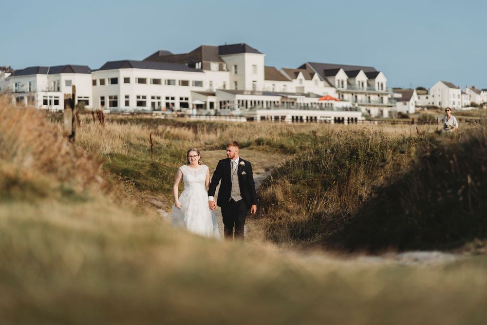 Bride and groom walking near Cliff Hotel wedding venue overlooking Cardigan Bay West Wales