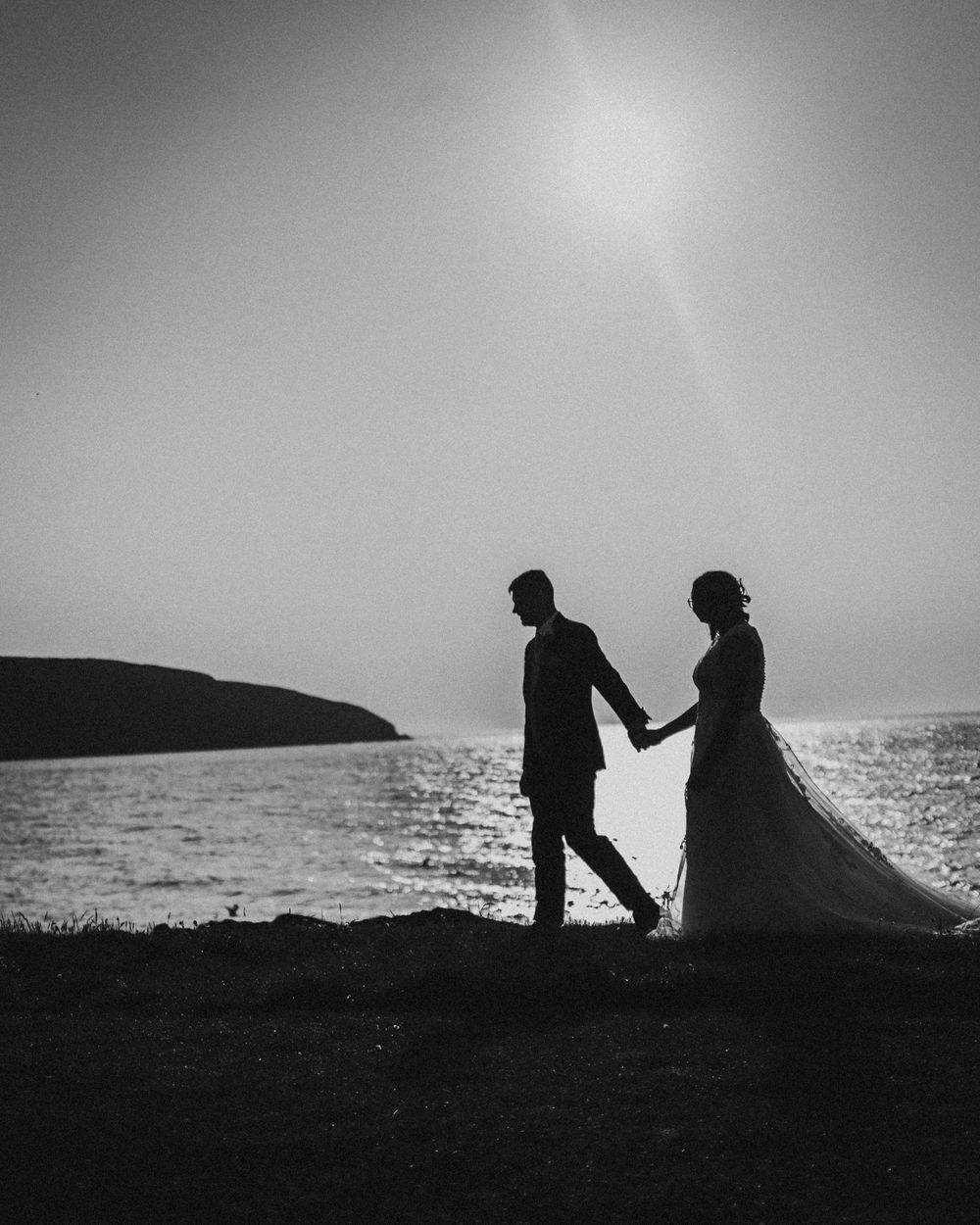 Bride and groom silhouette on Ceredigion coastline at sunset West Wales wedding